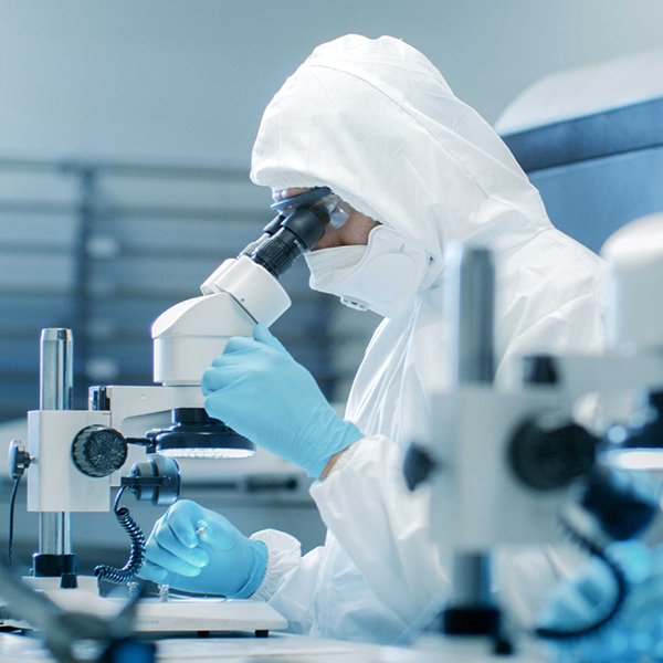 Image of a cleanroom user inspecting a microscope within a controlled environment.